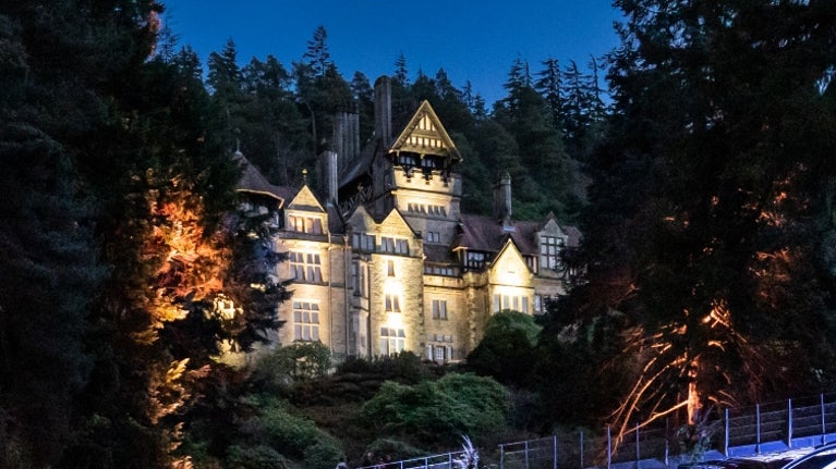 Cragside House illuminated by lights under twilight skies.